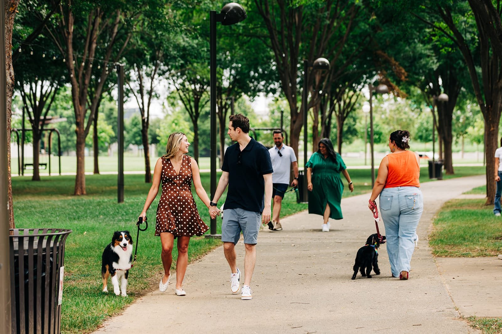 People walking dogs in a park.