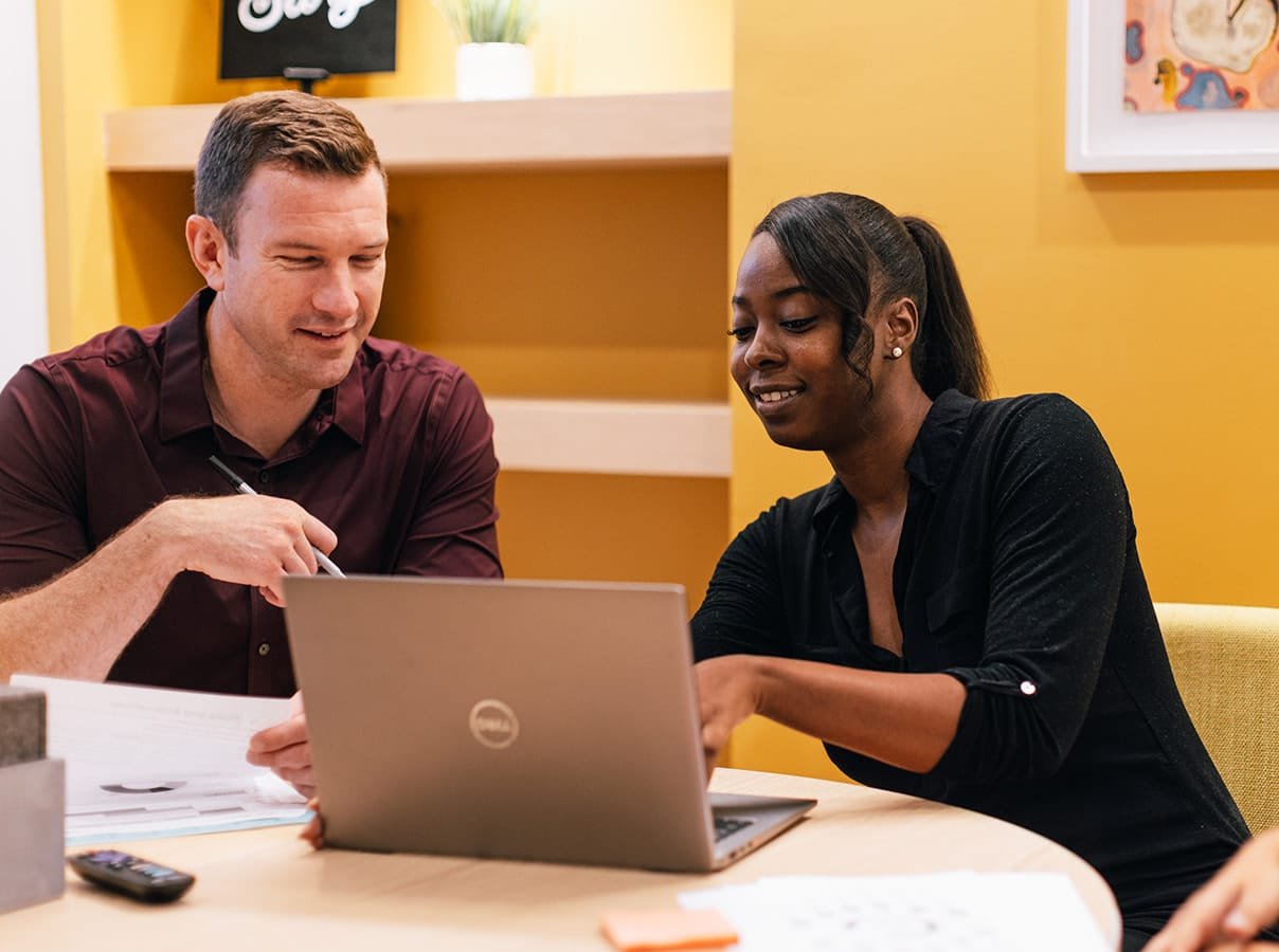 Two coworkers discussing over a laptop.