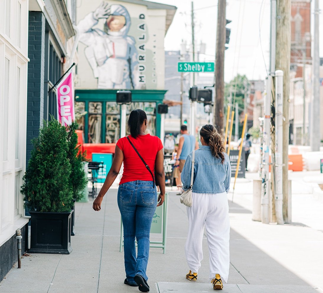 Two women walking on city sidewalk.